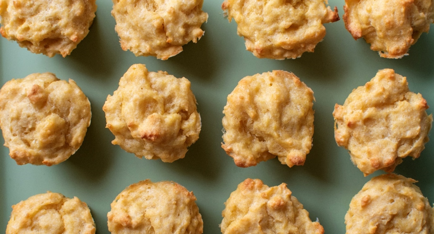 Twelve baked golden mini cornbread muffins arranged in rows on a plate.