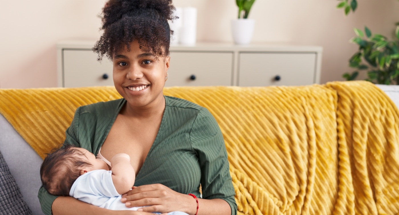 mother sitting on couch breastfeeding baby