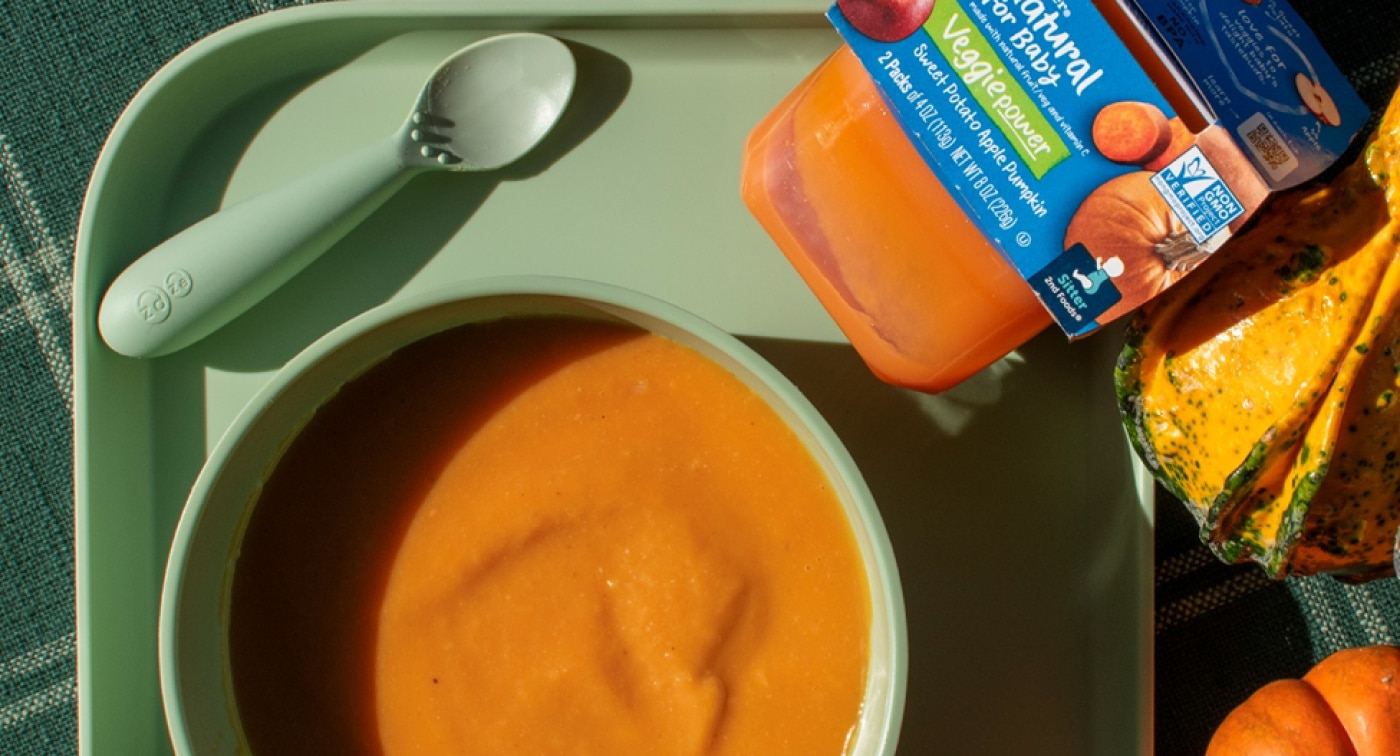 Bowl of pureed soup made with a container of Gerber Veggiepower puree and autumn gourds sitting on a table.