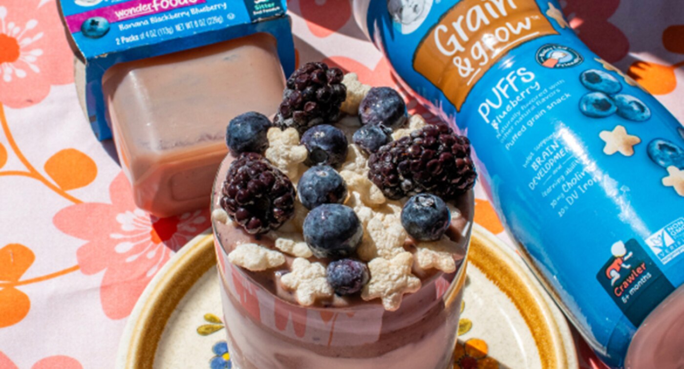 Banana blackberry blueberry smoothie in a glass topped with Gerber Puffs, and fresh blueberries and blackberries.