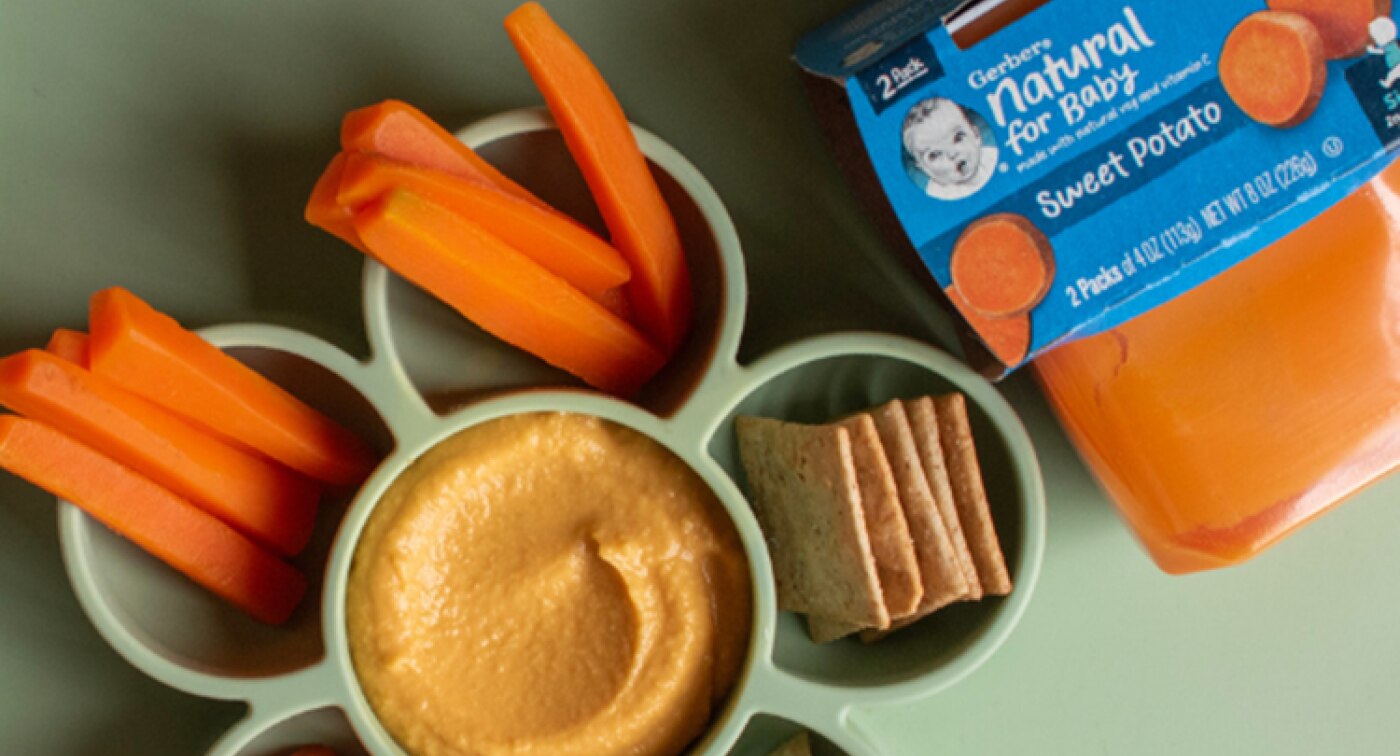 Divided bowl with carrot sticks, crackers, and hummus made from Gerber sweet potato puree.