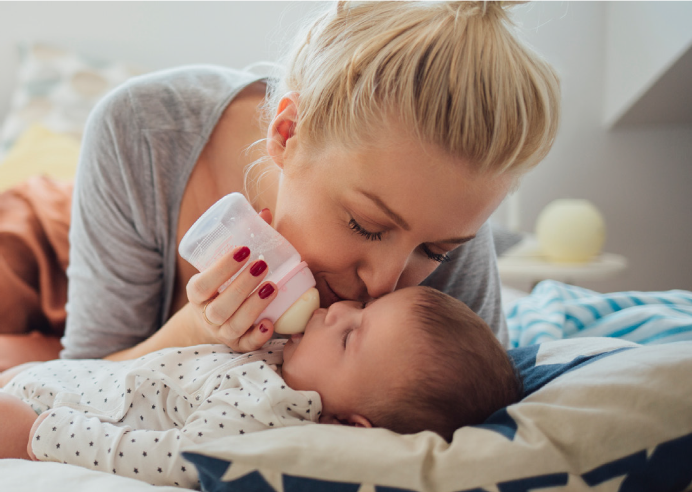 woman bottle feeding a baby laying on its back